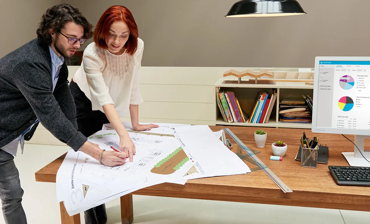 Architectural CAD drawings reviewed beside a large-format printer